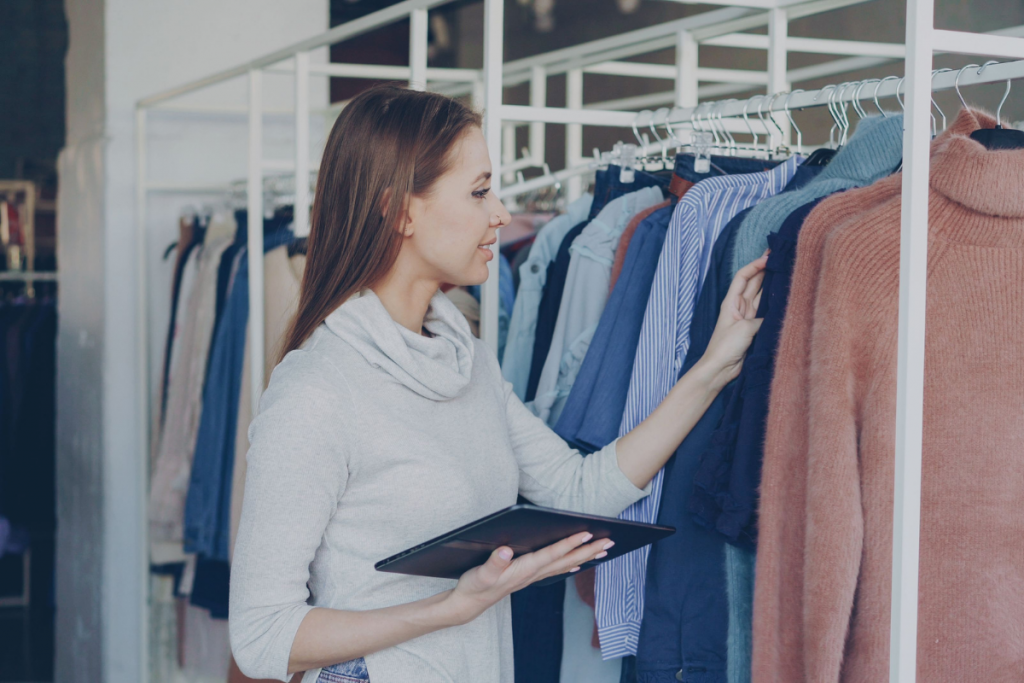Retail employee assisting a customer while using a tablet in a clothing store